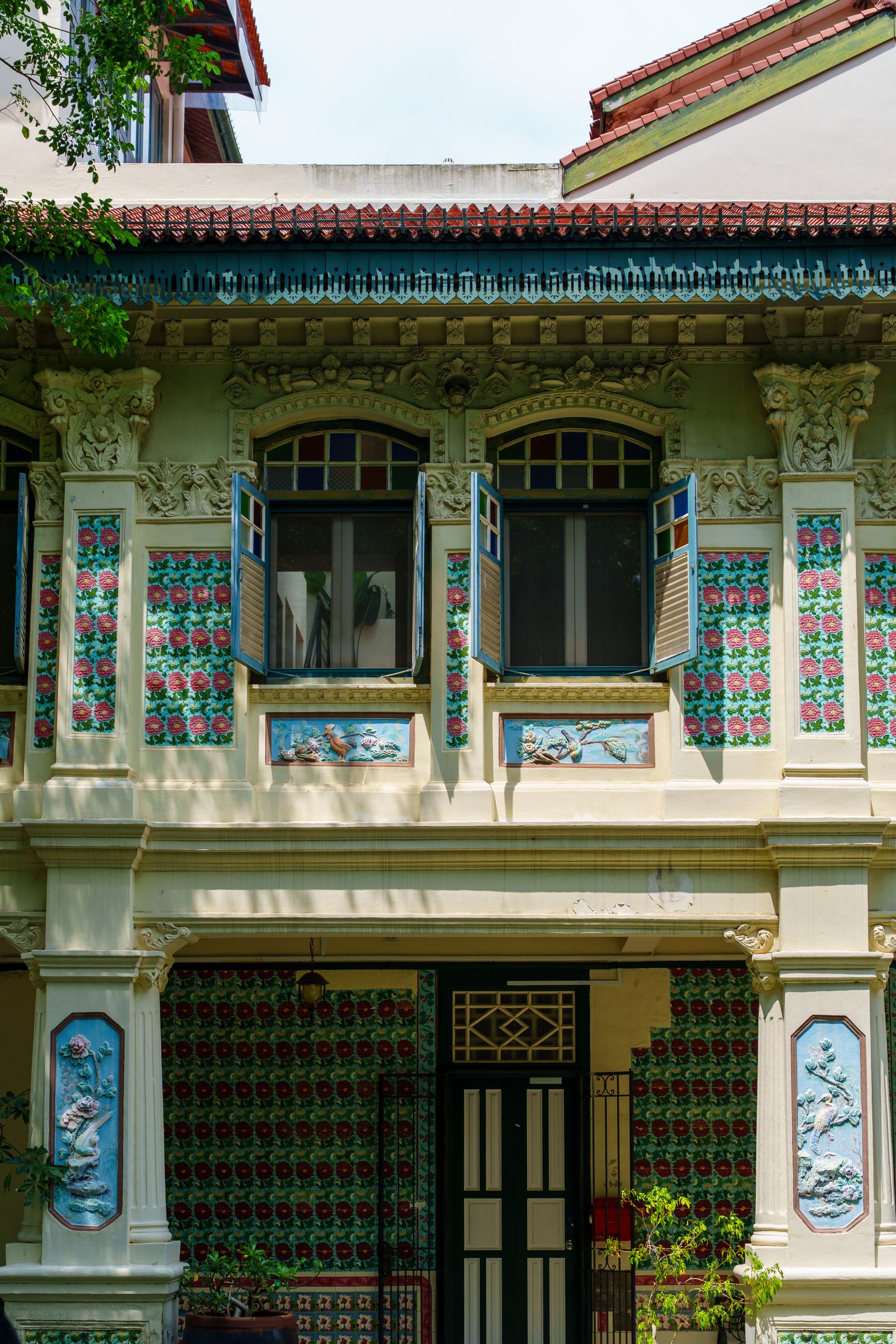 Restored Peranakan shophouse with floral tiles, shutters, and ornate plasterwork