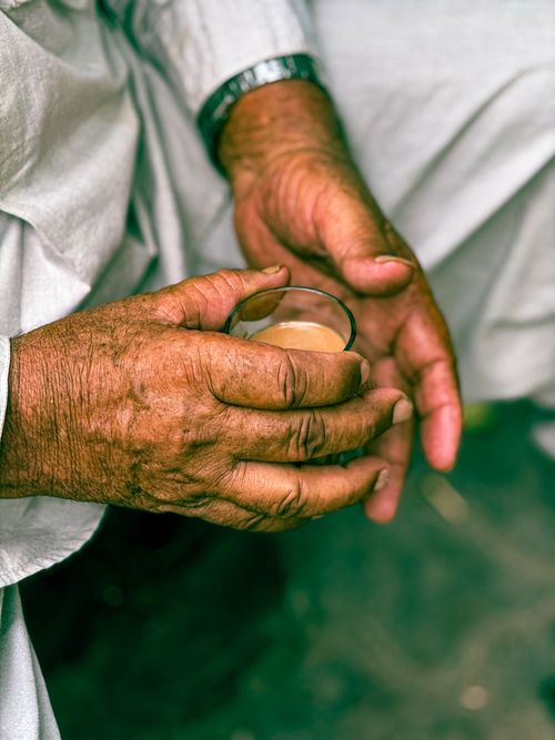 Free Close-up of elderly hands holding a glass of hot tea, symbolizing warmth and care. Stock Photo