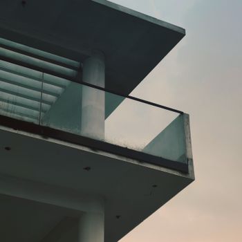 Sleek modern balcony in minimalistic architecture against a cloudy sky.