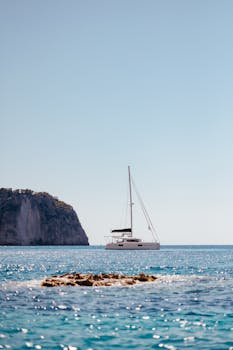 A serene yacht sails on the blue waters of Zakinthos, Greece under a clear sky.