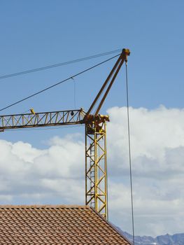 A yellow construction crane against a clear blue sky in Slingia, Trentino-Alto Adige.