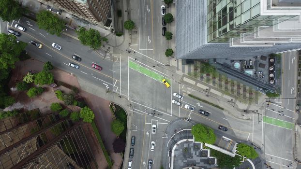 Aerial shot of a busy city intersection with cars and skyscrapers.