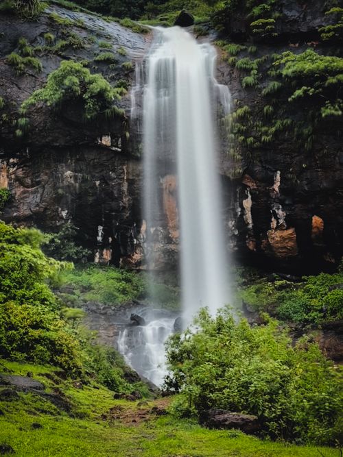 Free A stunning waterfall cascades over lush green cliffs, creating a serene scene in nature. Stock Photo