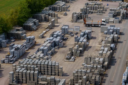 Aerial shot of a vast industrial yard with stacked bricks and a loading truck, captured on a clear day.
