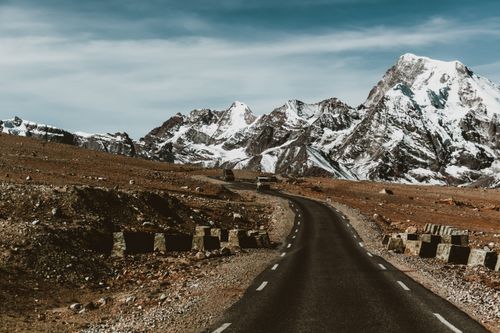 Free A stunning view of a winding road through snowcapped mountains, perfect for travel and adventure enthusiasts. Stock Photo