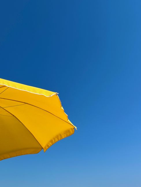 Bright yellow umbrella set against a vivid blue sky, capturing a perfect summer day.