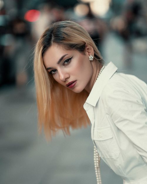Free Elegant woman in city street, posing with sophisticated attire and makeup. Stock Photo