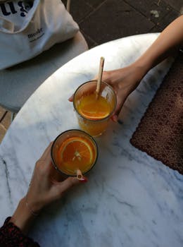 Two people enjoying fresh orange juice at an outdoor cafe with stylish decor.