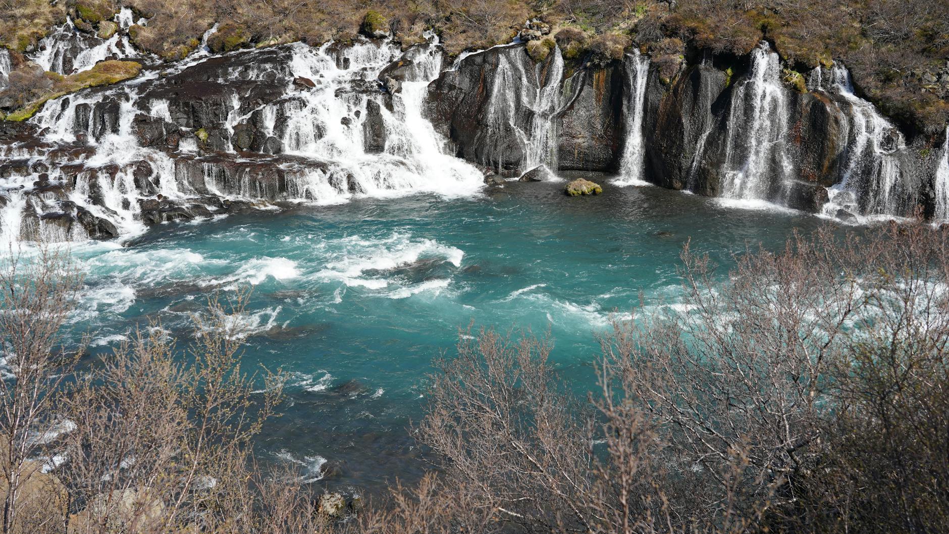 Spectacular view of Hraunfossar waterfall cascading into turquoise waters in Iceland.