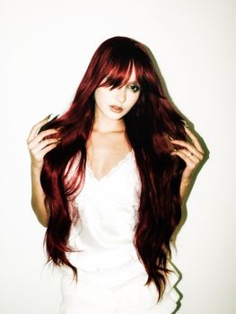 Striking portrait of a woman with long red hair in a white outfit, exuding modern elegance.