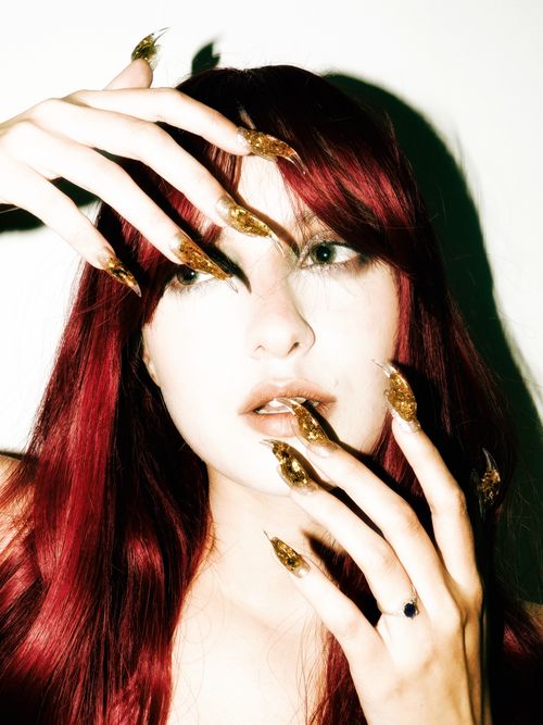Free Vivid portrait of a woman with red hair and artistic gold nails, highlighting modern style and creative beauty. Stock Photo