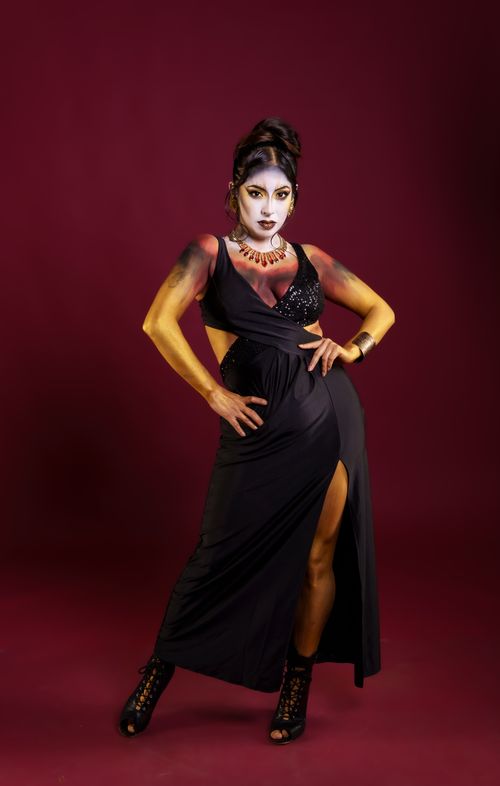 Free A striking portrait of a model with artistic makeup and elegant black dress against a maroon backdrop. Stock Photo