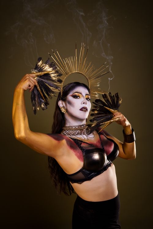 Free Captivating performer with artistic makeup, gold headdress, and feathers creates a dramatic and elegant presence. Stock Photo
