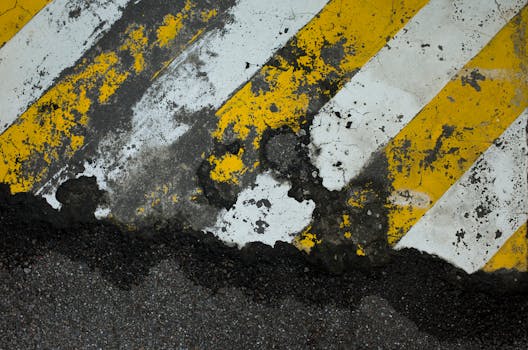 Close-up of cracked and weathered yellow and white road markings in Taipei, Taiwan.