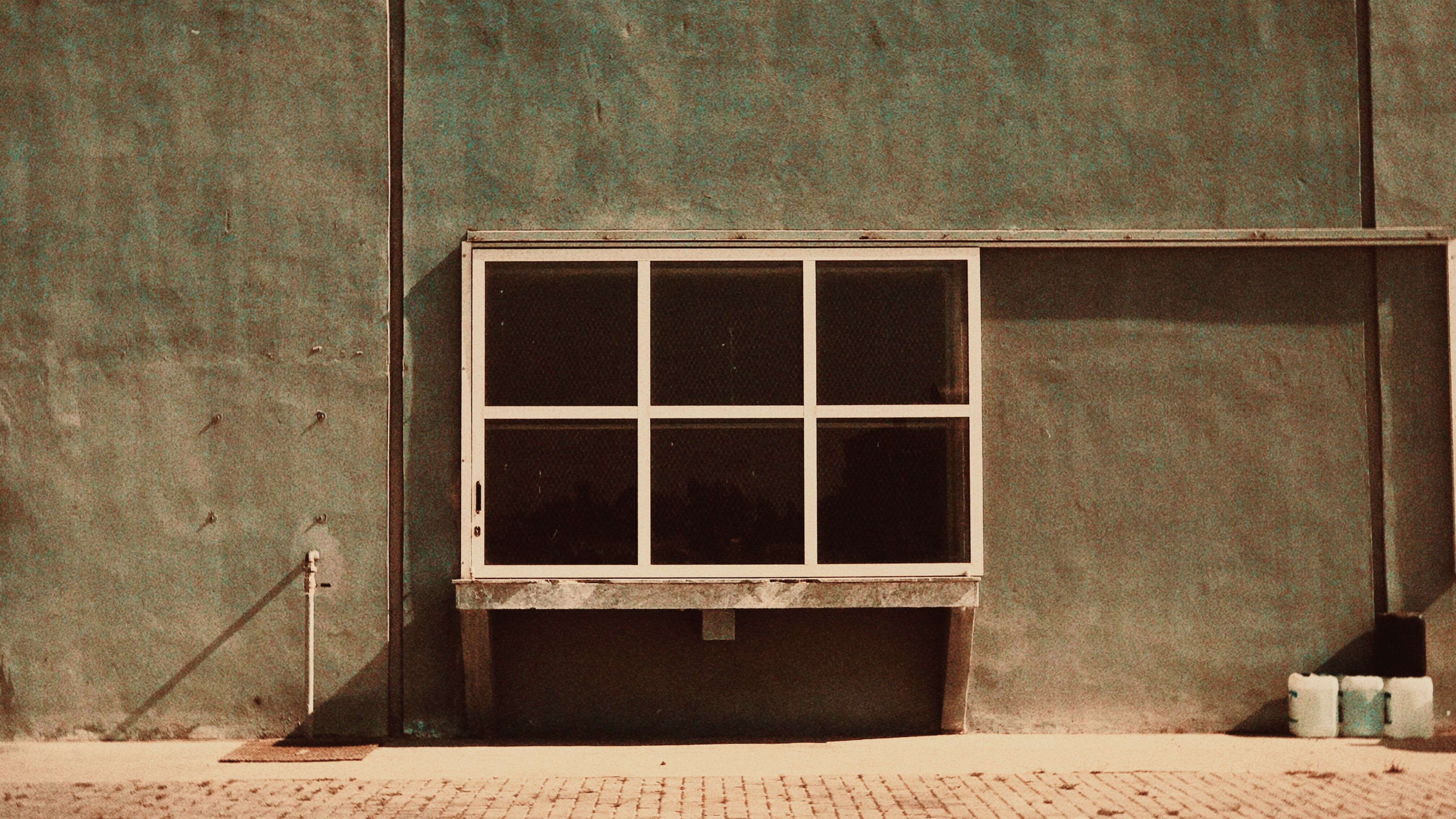 Artistic view of a rustic wall with a symmetrical window, exuding a vintage vibe.
