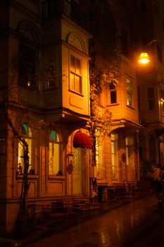 Warmly lit street cafe in Istanbul, Türkiye at night, showcasing vintage architecture and inviting atmosphere.