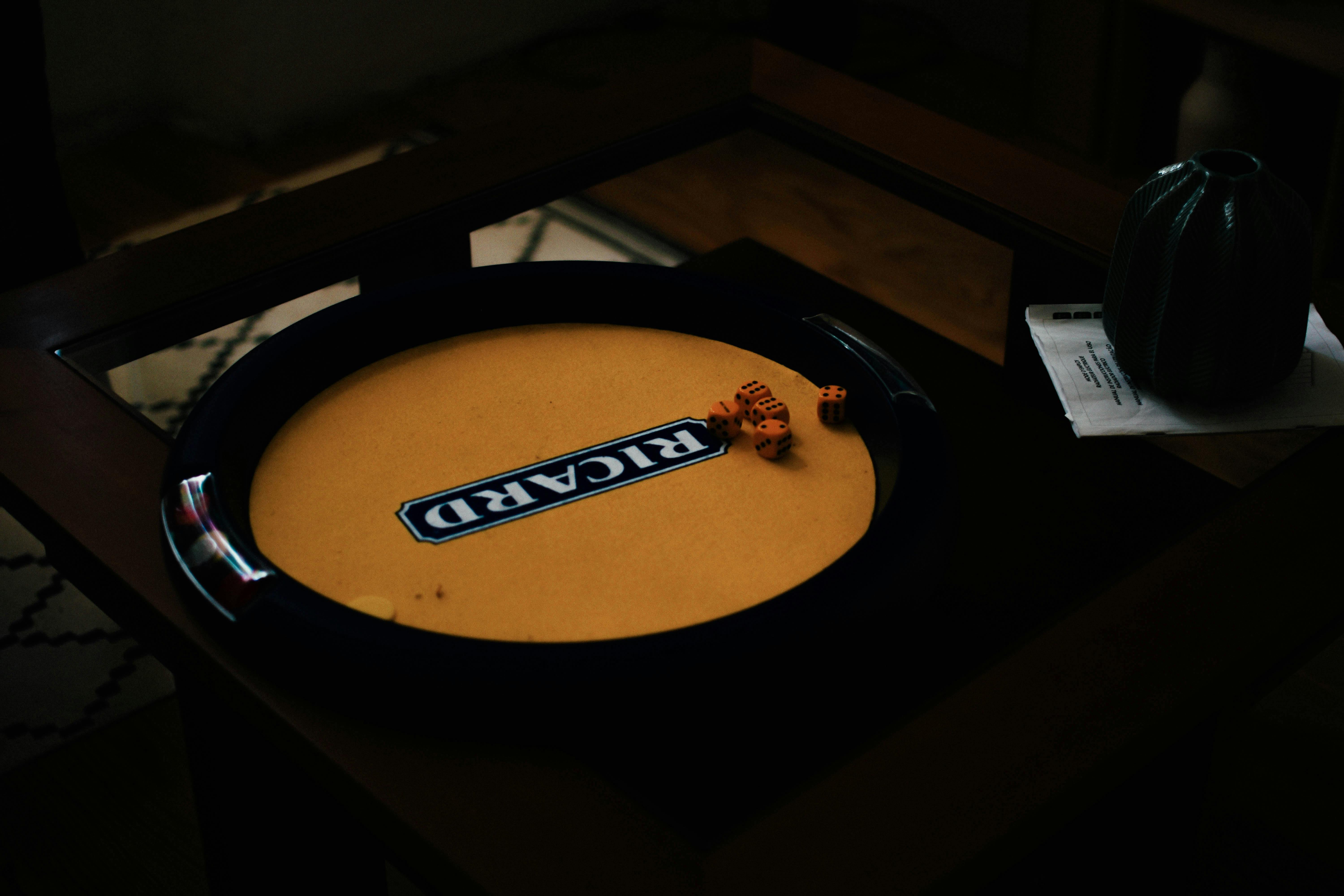 無料 柔らかな照明がムーディーな雰囲気を醸し出す木製のテーブルに置かれたサイコロゲームのクローズアップ。 写真素材