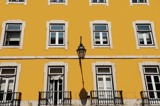 Yellow building facade with classic windows and a lamp in Lisbon, Portugal.
