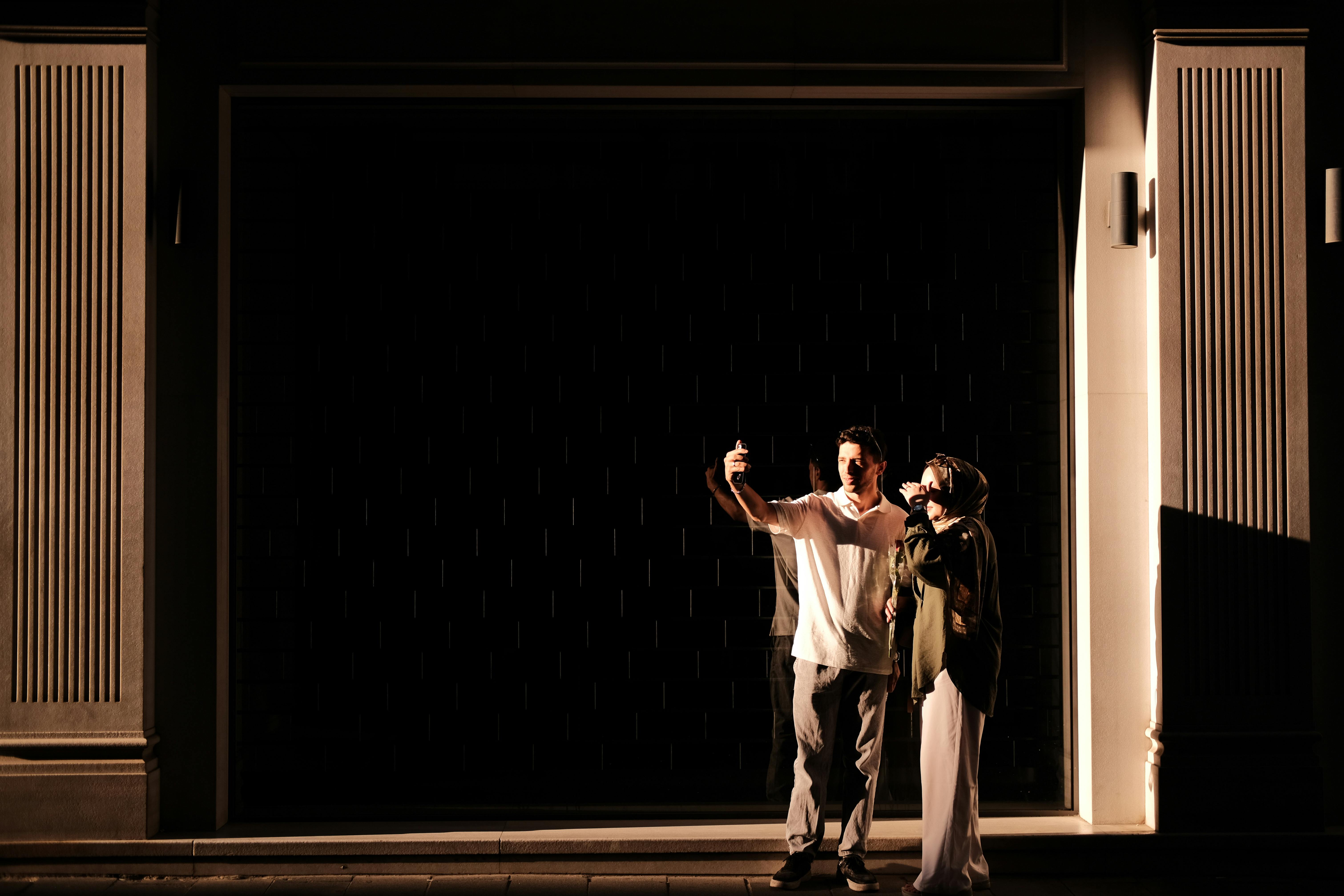 Δωρεάν Νεαρό ζευγάρι βγάζει μια selfie στο απαλό φως του ήλιου σε ένα κομψό, μινιμαλιστικό φόντο. Φωτογραφία από στοκ φωτογραφιών