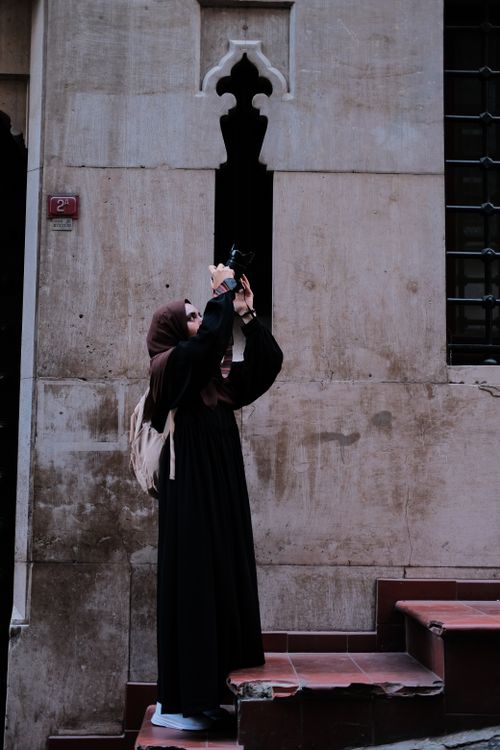 Free Woman in traditional attire capturing architectural details with a camera. Stock Photo