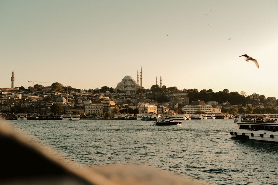 Breathtaking view of Istanbul with boats on the Bosphorus and iconic Suleymaniye Mosque at sunset.