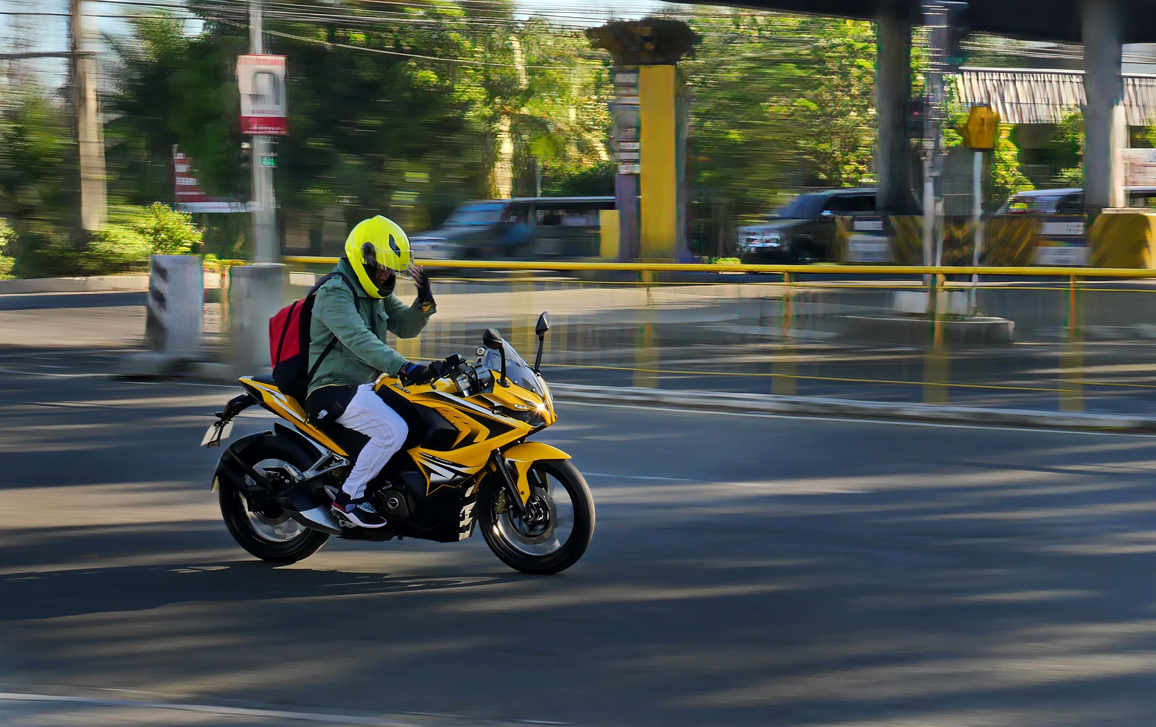 Gratuit Un motocycliste portant un casque jaune conduit une moto jaune dans une rue de la ville d'Iloilo. Photos