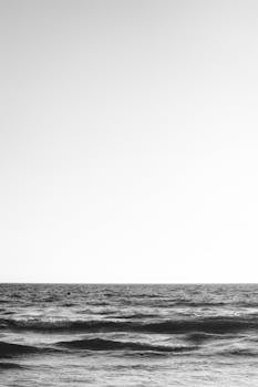 A serene black and white seascape capturing the ocean waves under an expansive sky.