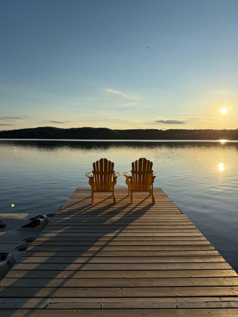 Peaceful sunrise view over lake with empty wooden chairs on a dock at Dwight, Ontario.