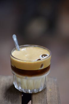 A creamy and rich Vietnamese egg coffee in a glass with a spoon, showcasing the layered texture and inviting appearance.