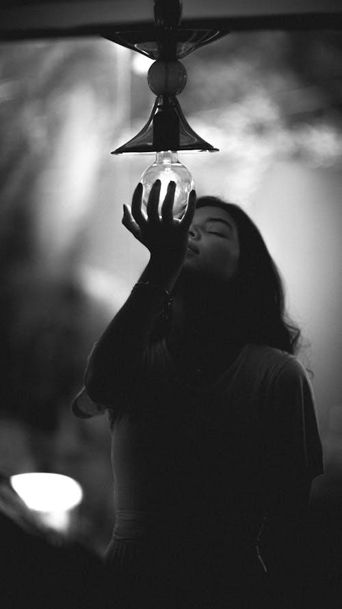 Grayscale Photo of Person Holding Light Bulb