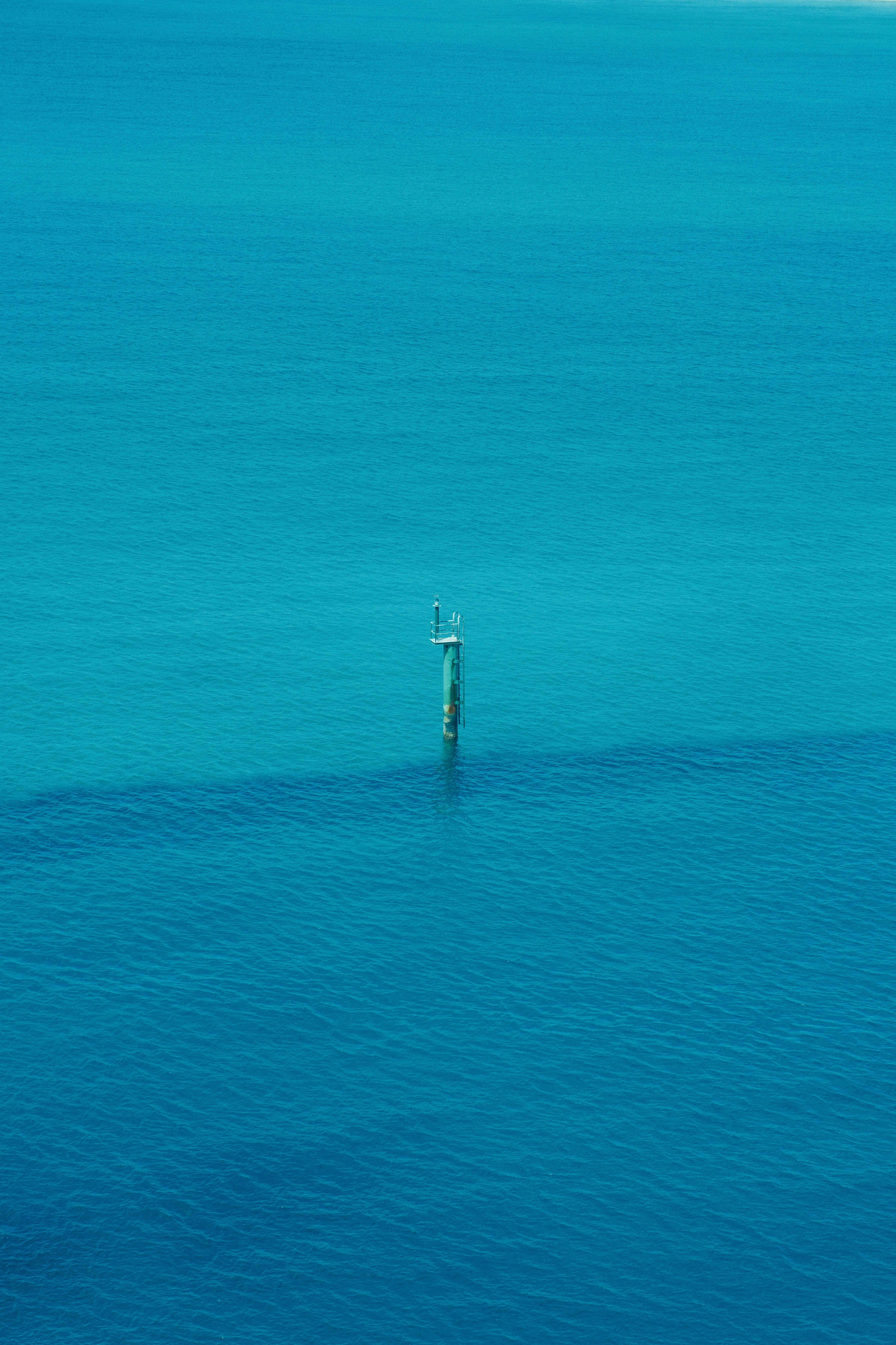 Aerial view of a single buoy in tranquil turquoise waters, highlighting solitude and serenity.
