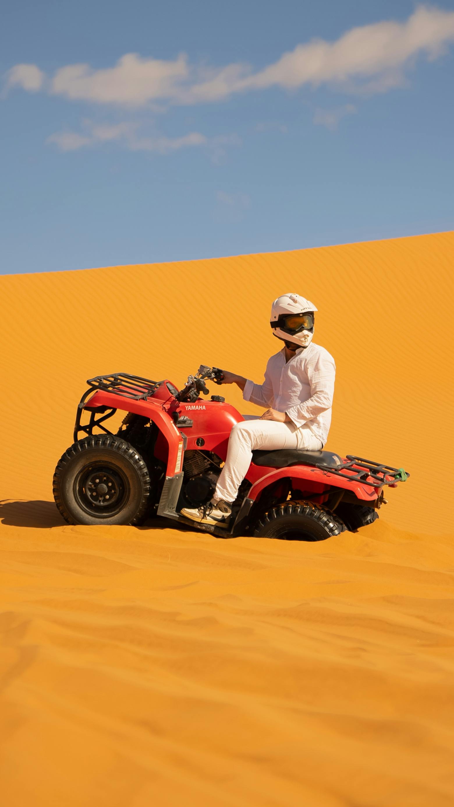 A person riding an ATV across the vibrant dunes of the Moroccan Sahara Desert in Merzouga.