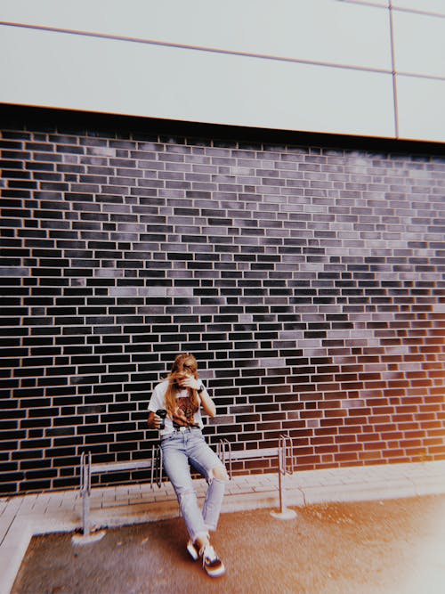 Woman Sitting on Bench Beside Wall