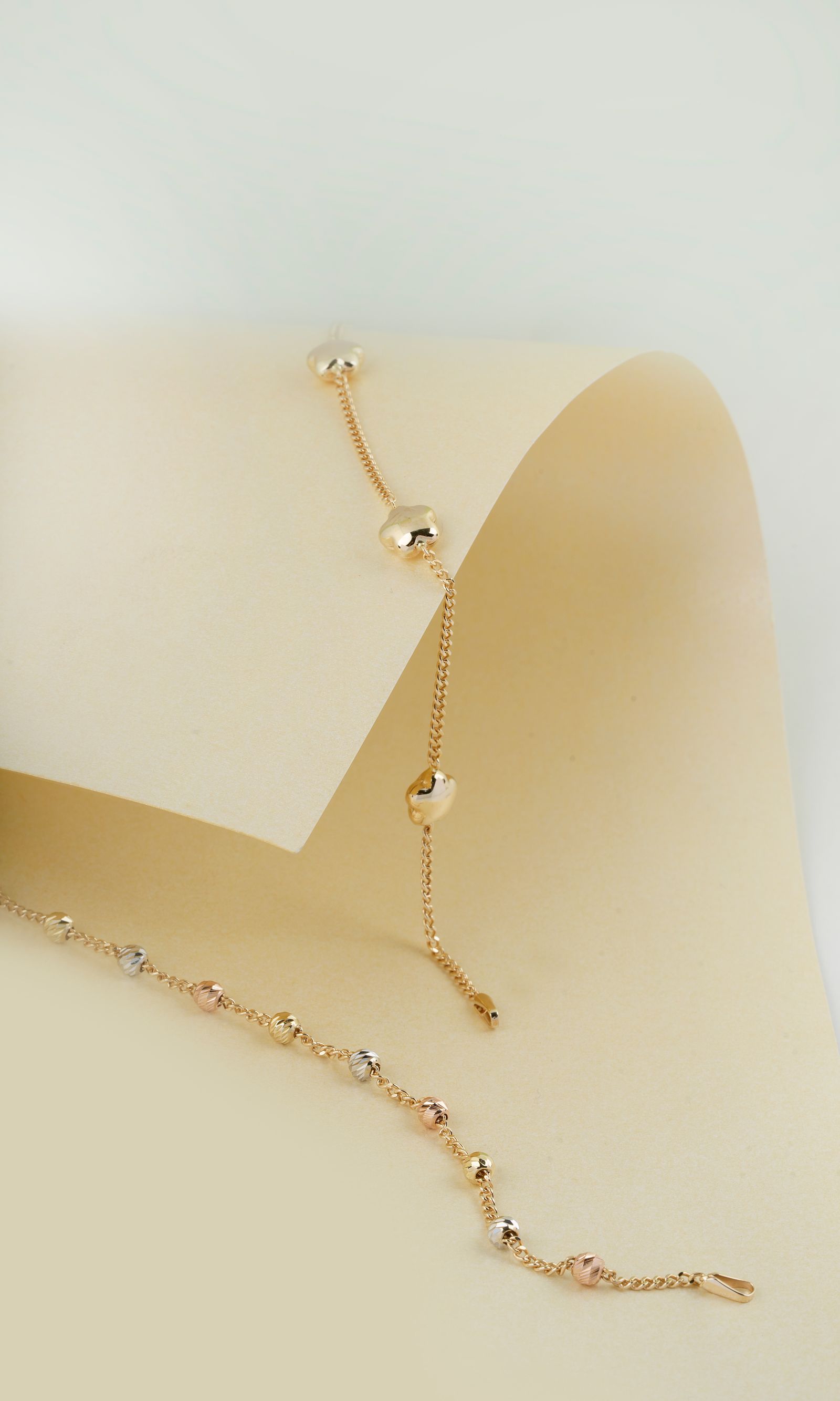 Elegant gold jewellery displayed on a soft cream background