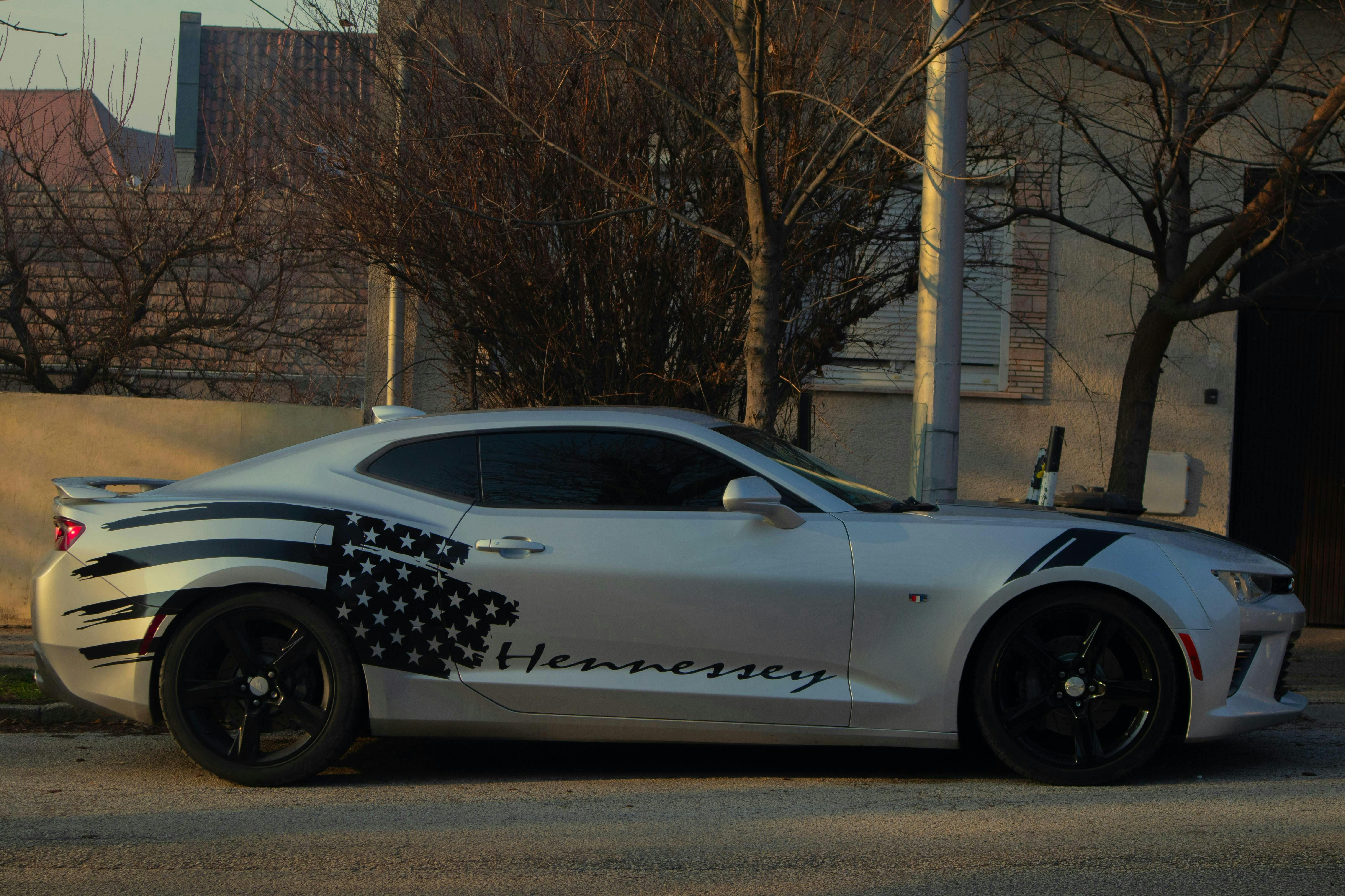 Sleek sports car with American flag design parked on urban street during daytime.