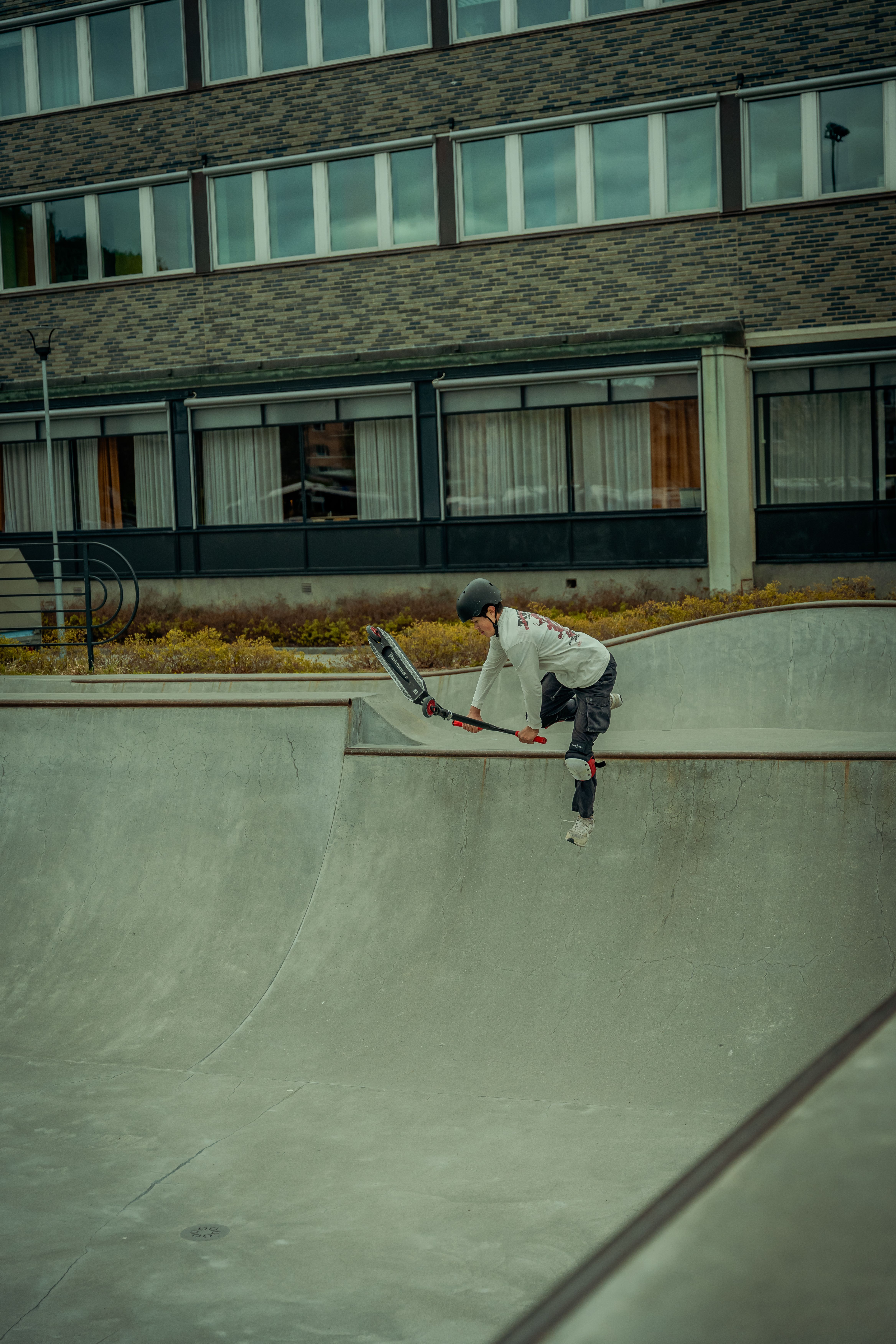 A young scooter rider in mid-action at an urban skatepark, showcasing balance and skill.
