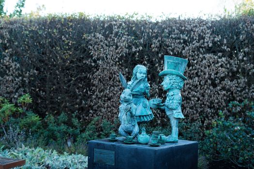 Bronze statue of Alice, Mad Hatter, and White Rabbit in a New Zealand garden.