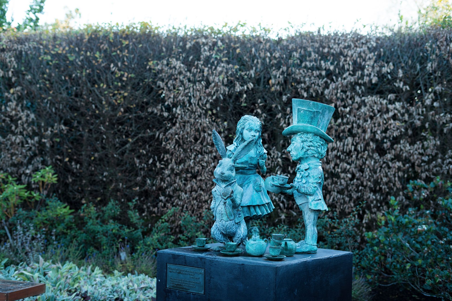 Bronze statue of Alice, Mad Hatter, and White Rabbit in a New Zealand garden.