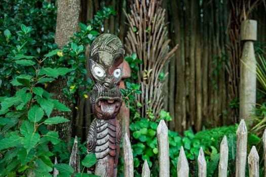 A traditional Maori carving surrounded by lush greenery in a New Zealand garden, showcasing cultural heritage.
