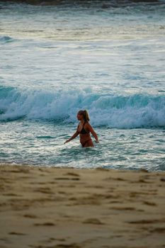 A woman in a bikini enjoying the ocean waves on a sunny beach day.