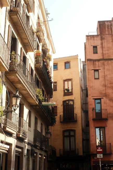 Sunlit historic buildings with rustic balconies in Barcelona's vibrant old town.