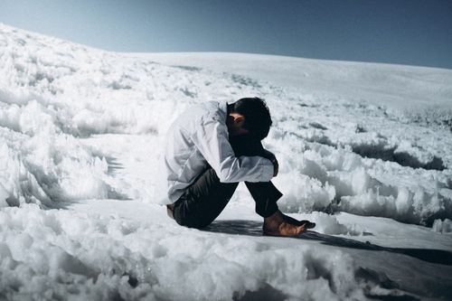 Free A person sits alone on a snow-covered landscape, evoking feelings of isolation and contemplation. Stock Photo