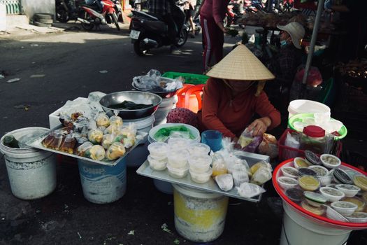 A vibrant street food market with an array of local dishes and a vendor wearing a conical hat.
