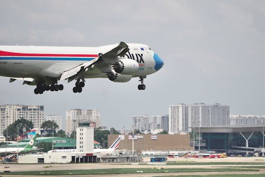 A cargo airplane approaching an urban airport for landing with cityscape in the background.