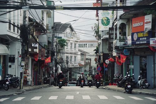Free Vibrant street view in Vietnam showcasing motorcycles, bustling shops, and urban life. Stock Photo