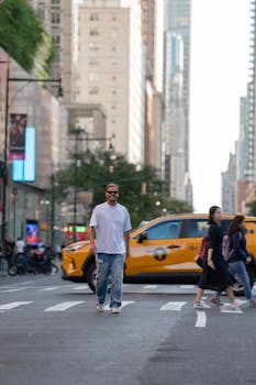 Casual pedestrians crossing a vibrant New York City street with iconic taxi.