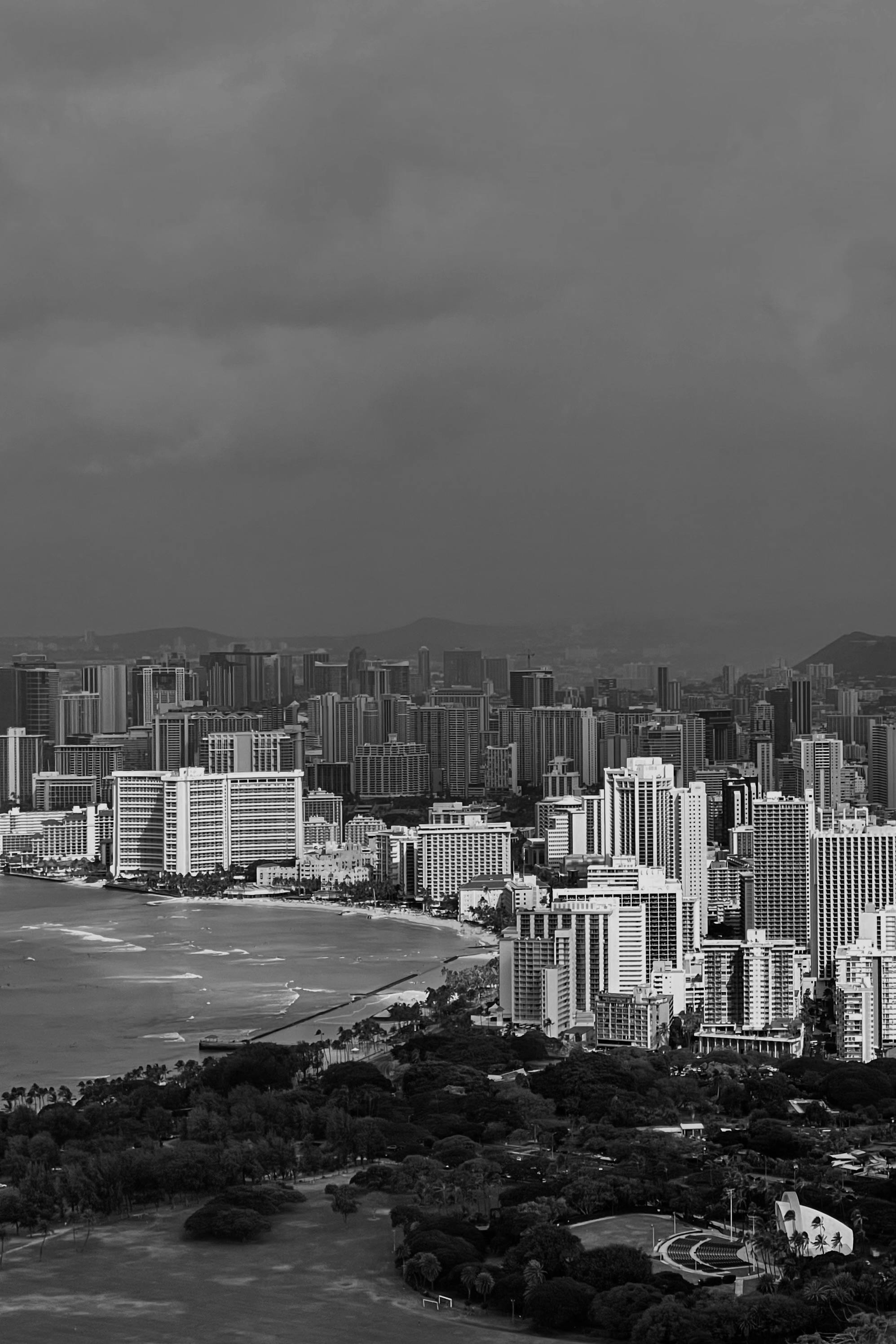 Dramatic aerial view of a city skyline meeting the ocean under a stormy sky.