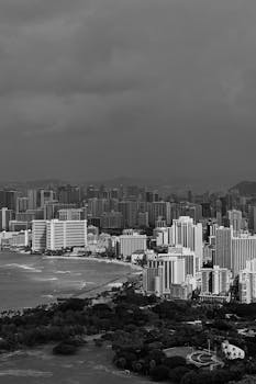 Dramatic aerial view of a city skyline meeting the ocean under a stormy sky.