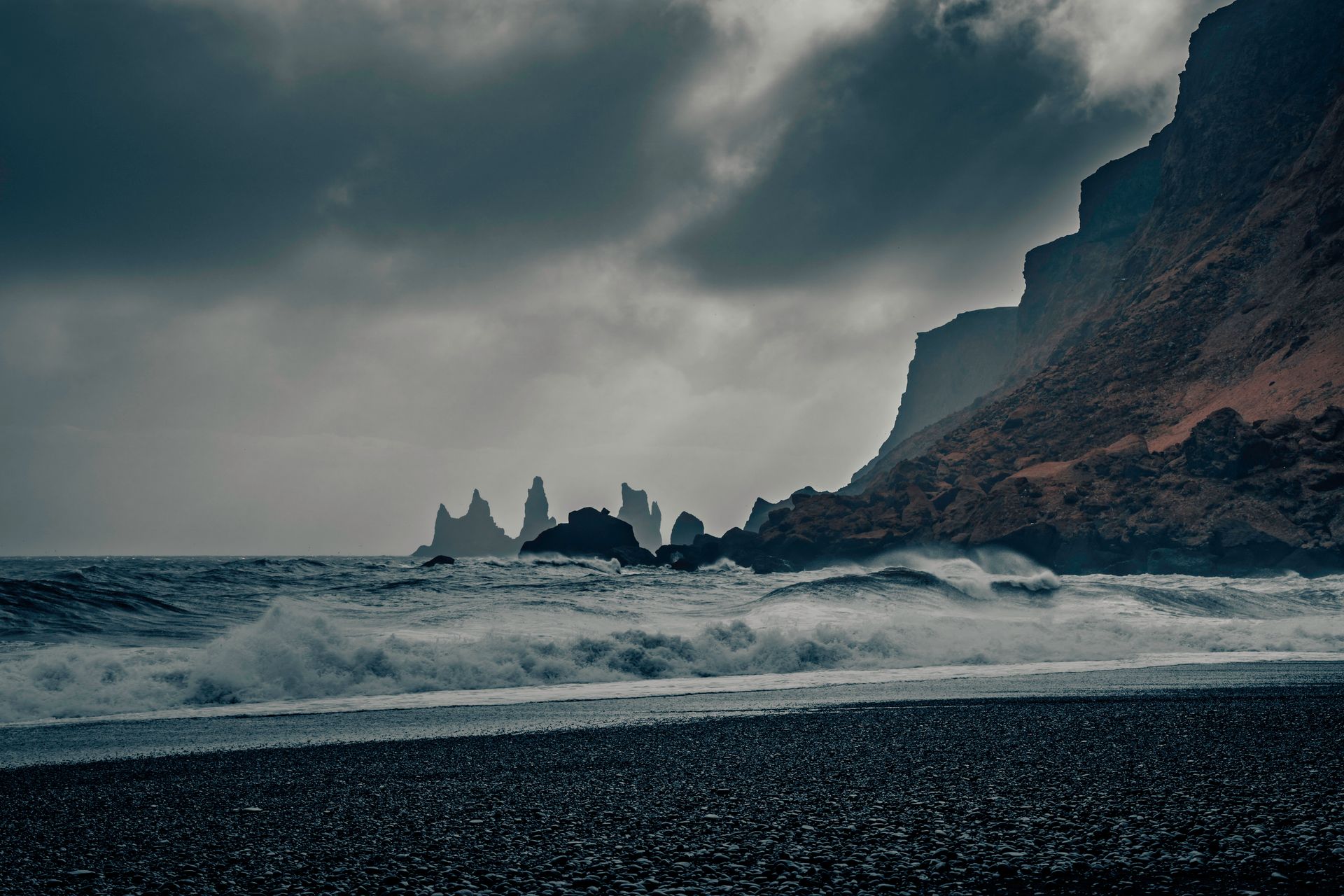 Majestic view of Iceland's rugged coastline with crashing waves under a moody sky.