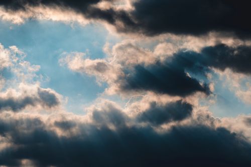 Free Majestic clouds with sunrays peeking through, creating a dramatic sky scene. Stock Photo
